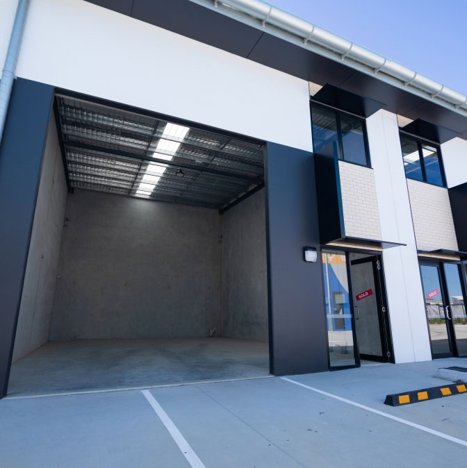 http://An%20industrial%20building%20with%20a%20parking%20lot%20in%20front%20of%20it.