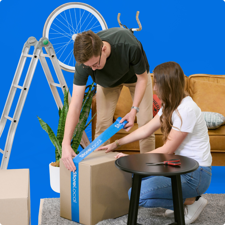 moving-house-img A man and woman unpacking boxes on a blue background.