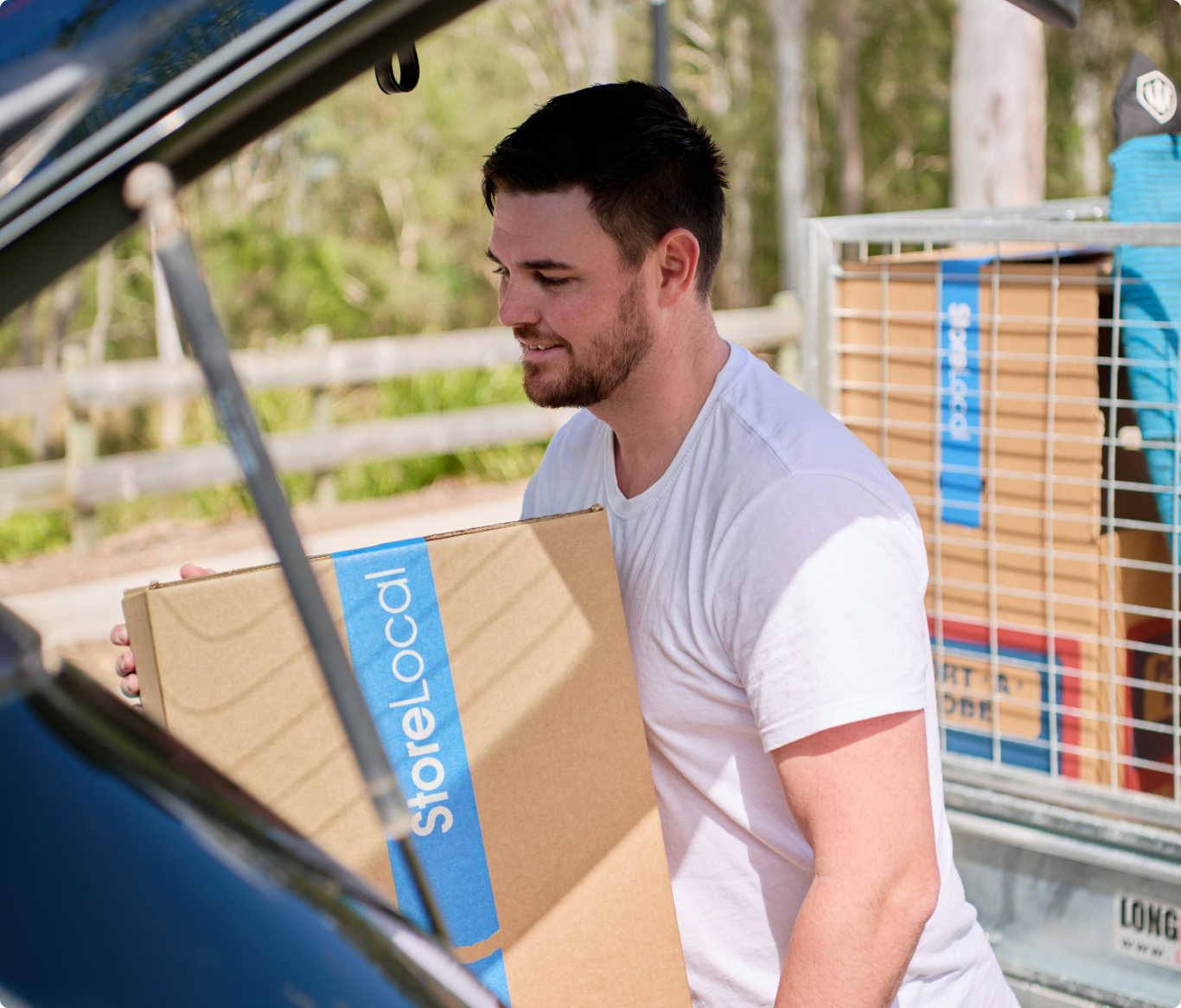 A man loading a box into the trunk of a car.