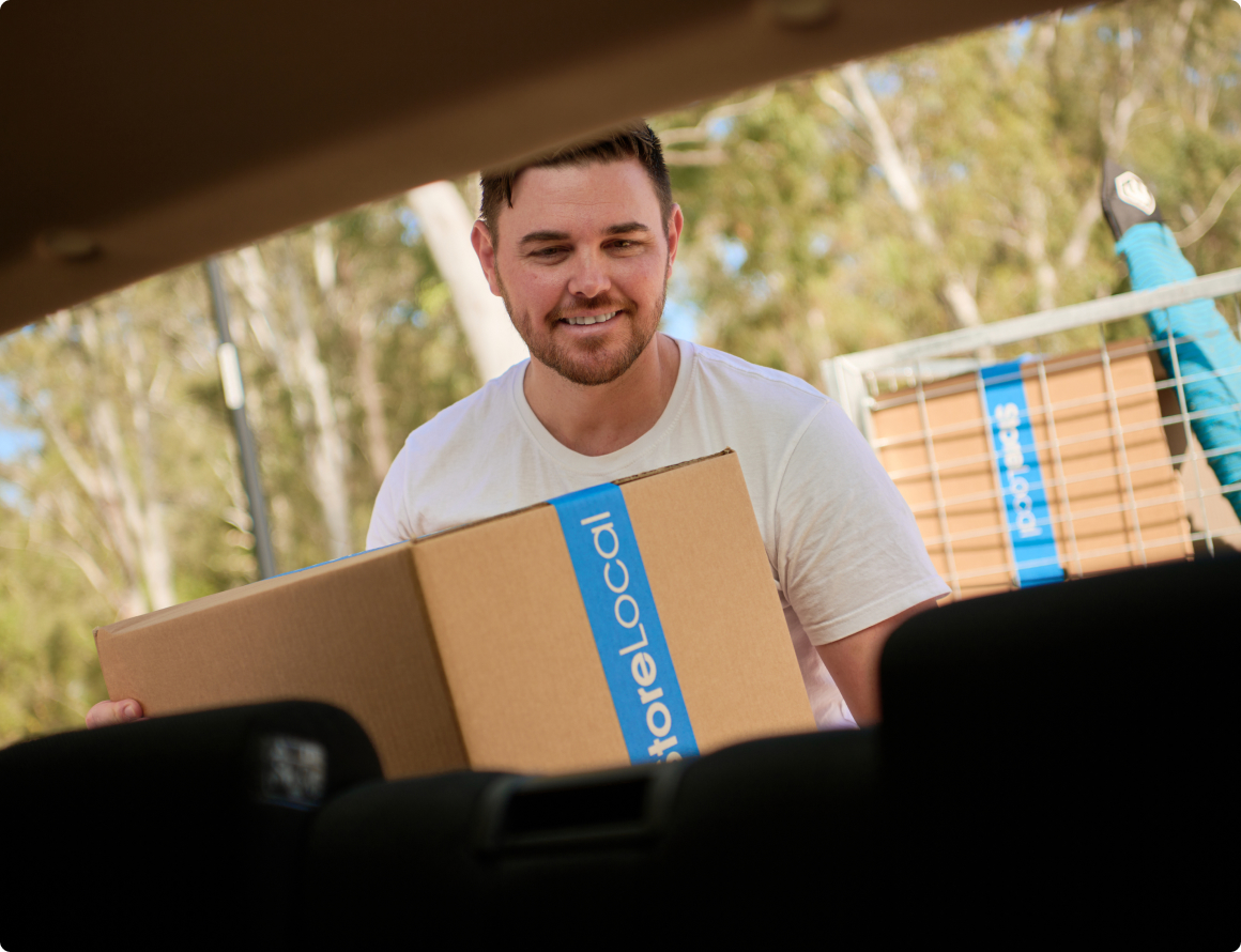 region-img A man holding a box in the back seat of a car.
