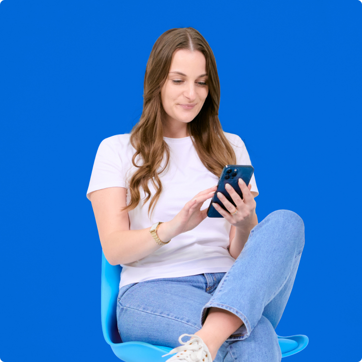 size-guidance-img A woman sitting on a blue chair looking at her phone.